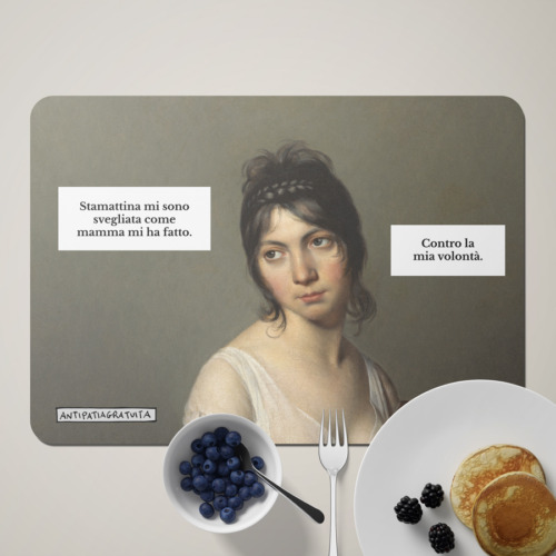 Tovaglietta americana Antipatiagratuita apparecchiata per la colazione, con una ciotola di mirtilli, una forchetta, un piatto di pancake con more e un tovagliolo bianco. Sopra, il ritratto di una giovane donna d&rsquo;epoca dall&rsquo;aria scocciata con i fumetti &ldquo;Stamattina mi sono svegliata come mamma mi ha fatto.&rdquo; e &ldquo;Contro la mia volont&agrave;.&rdquo;