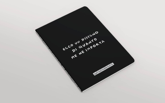 Quaderno nero con angoli arrotondati e cucitura a vista, inclinato in prospettiva su sfondo grigio chiaro. In copertina la frase scritta a mano in bianco “Ecco un disegno di quanto me ne importa” e, in basso, l’etichetta “Antipatiagratuita”.