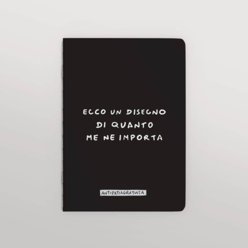 Quaderno nero con angoli arrotondati visto frontalmente su sfondo grigio chiaro. Sulla copertina, in bianco e in stile scritto a mano, la frase “Ecco un disegno di quanto me ne importa” e in basso l’etichetta “Antipatiagratuita”.